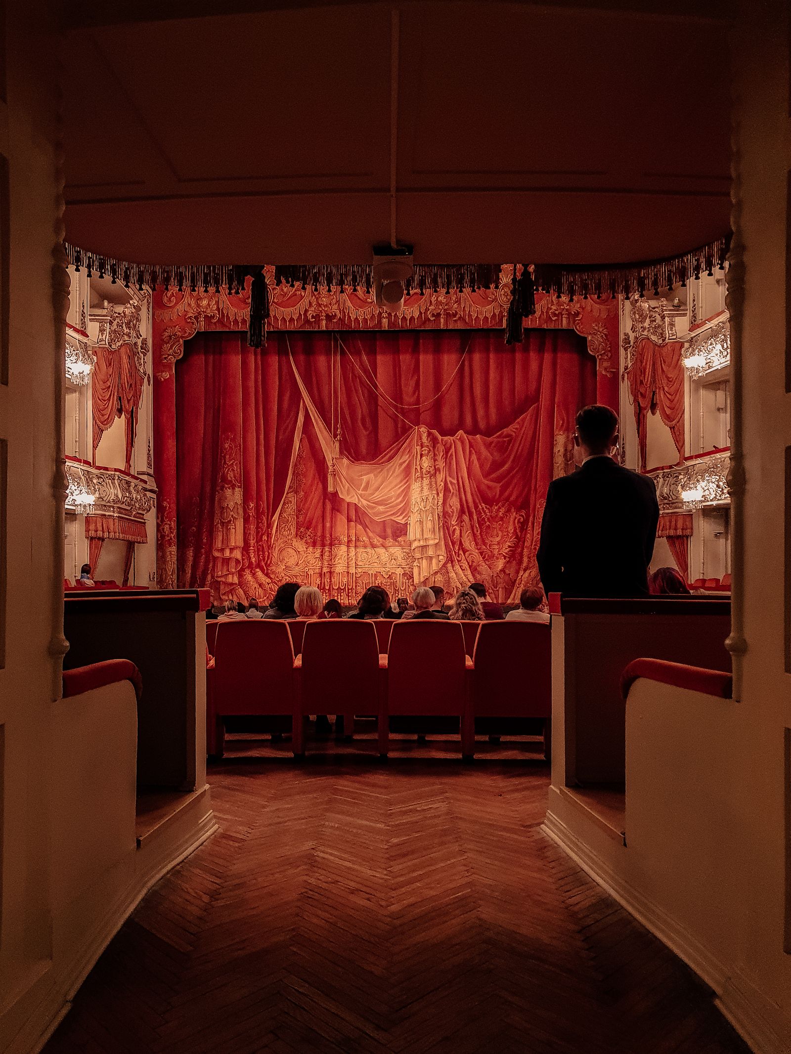A warmly lit stage with rich velvet curtains
